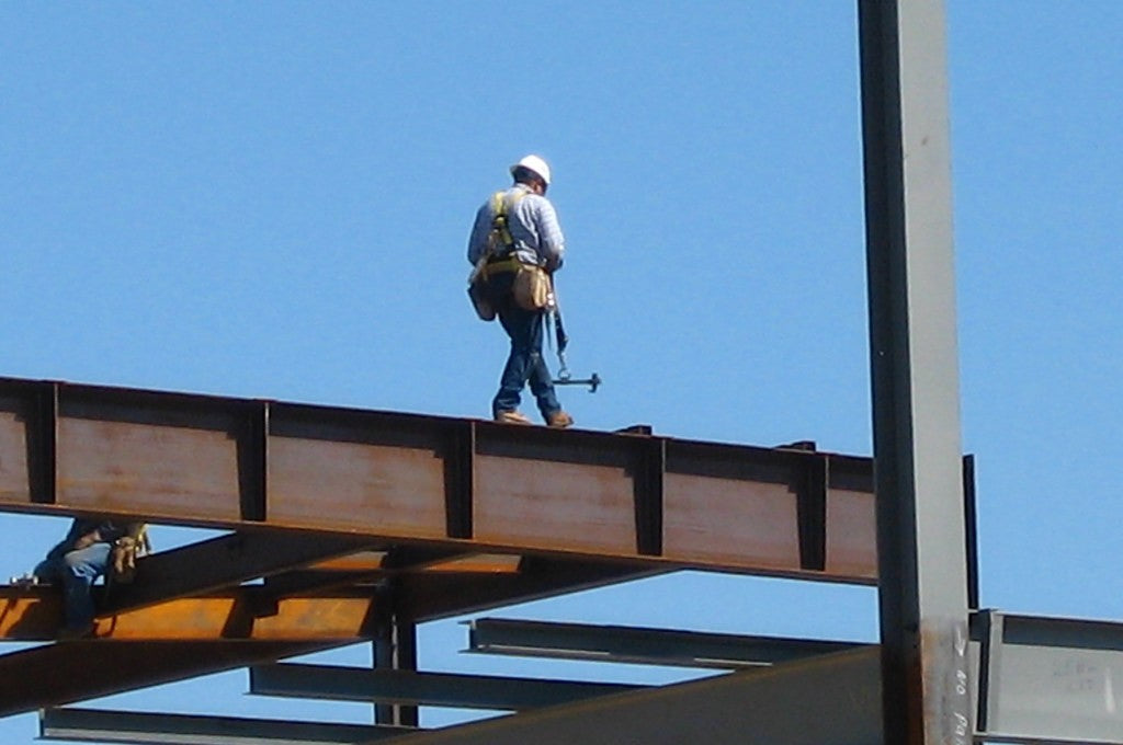 A construction worker walking across a beam.