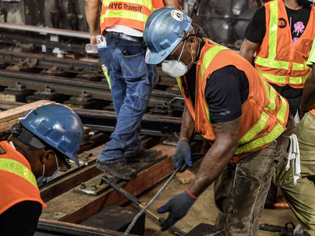 A group of construction workers placing railroad tracks.