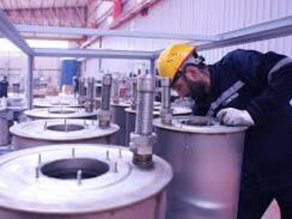 A factory worker bending over while working.