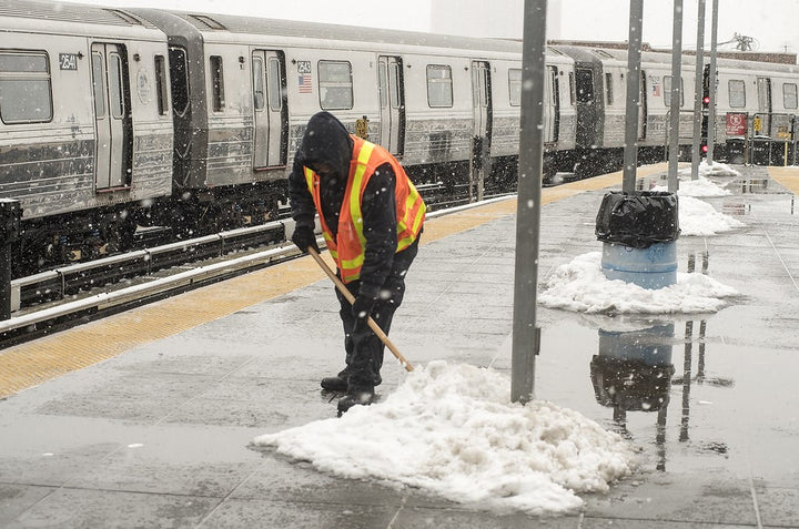 A man with a safety vest clearing snow.