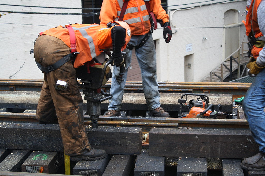 A construction worker using a jackhammer to drill into the ground.