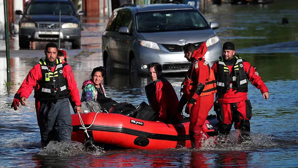 Rescue workers helping a woman during a flood.