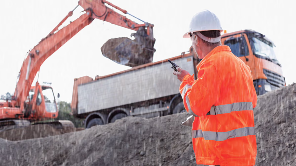 Construction worker using a walkie talkie in the rain.