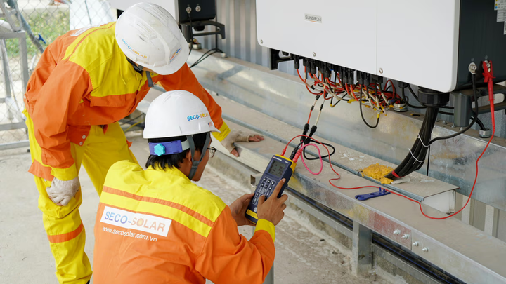 Two electrical workers using a device to read something.