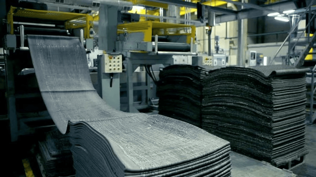 Layers of rubber lined up as they come off of the conveyer belt in a factory.