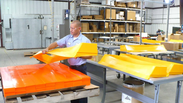 A factory worker peeling a rubber slab.