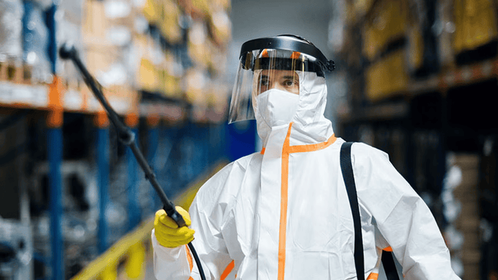 A man with a chemical sprayer walking down an aisleway.