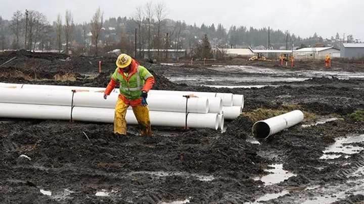 A construction worker slowly walking through mud.