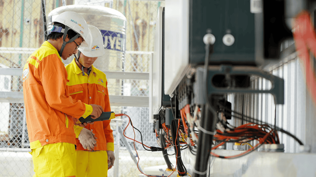 Two electrical workers reading an electrical measuring device.