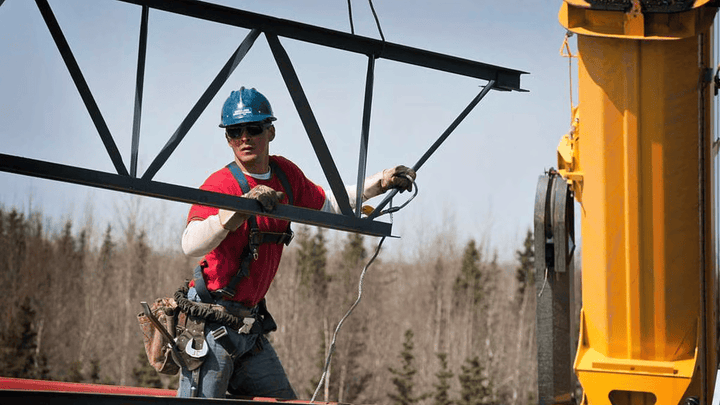 Construction worker guiding a beam.