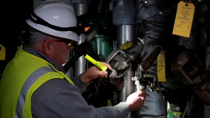 Construction worker twisting a gauge in the dark with a flashlight shining on it.