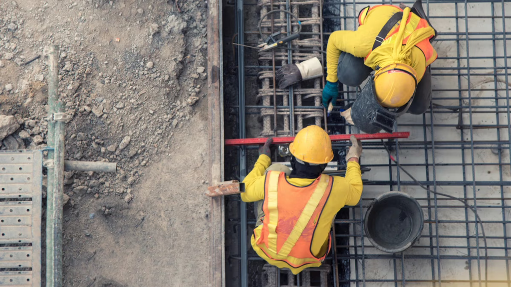 Two construction workers leveling part of a building.