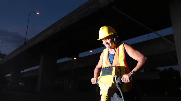 Construction worker using a jack-hammer in the dark.