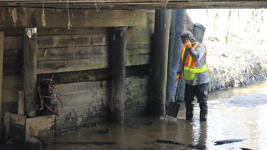 Construction worker with a shovel under a bridge.