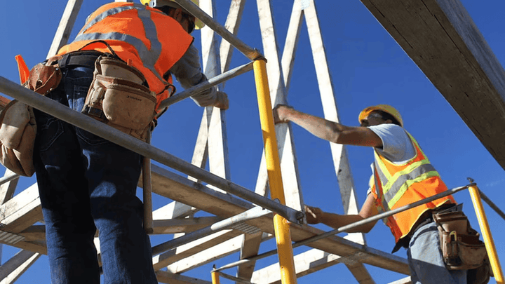 Construction workers guiding a beam.