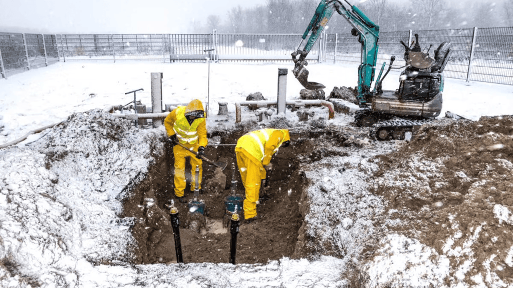 Construction workers digging a tunnel in snowy weather.