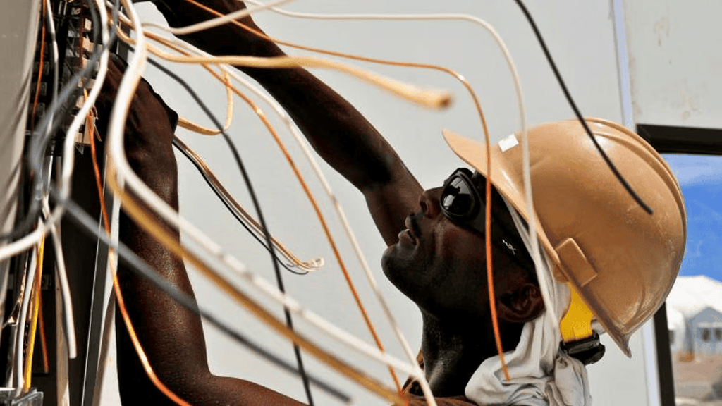 An electrician working on a panel of wires.