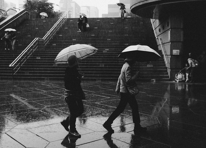 Groups of people walking through the rain with umbrellas.