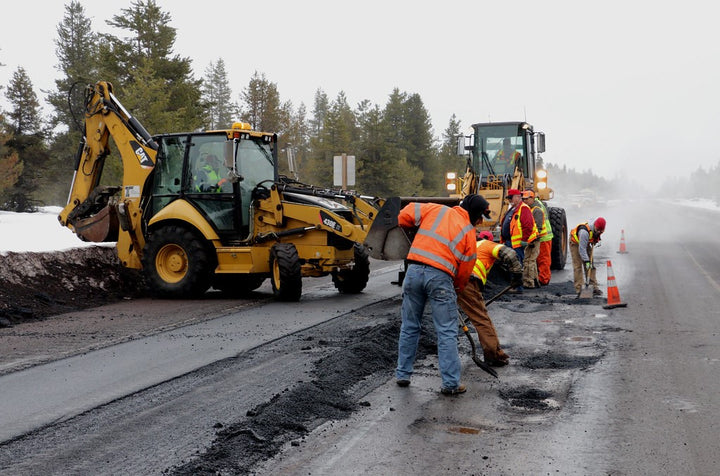 Construction workers digging up concrete.